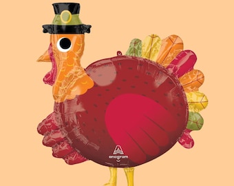 May include: A red, orange, and green foil balloon turkey with a black top hat and a white face. The balloon has the word "anagram" printed on it.