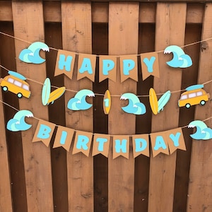 May include: A brown paper banner with the words "Happy Birthday" in blue letters. The banner is decorated with blue and white waves, yellow surfboards, and yellow vans.