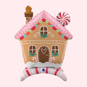 May include: A pink and brown gingerbread house balloon with a candy cane and a gingerbread man on top. The balloon is decorated with white frosting and candy canes.