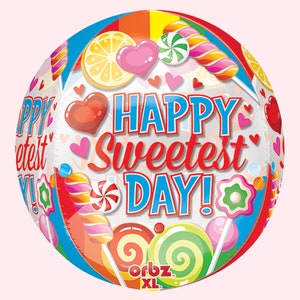 May include: A round, clear balloon with a colorful candy theme. The balloon features the text "HAPPY Sweetest DAY!" in blue and red, along with illustrations of lollipops, hearts, and citrus slices. The balloon is an Orbz XL.