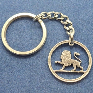 May include: Silver key chain with a lion cut out of a coin. The coin has a beaded edge.