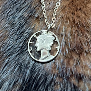 Könnte beinhalten: Eine silberne Halskette mit einem silbernen Münzenanhänger, der ein Profil eines Frauenkopfes zeigt. Die Münze trägt das Jahr 1942.