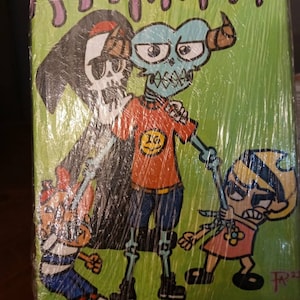 Könnte beinhalten: Eine handgemalte Leinwand mit vier Comicfiguren. Die Figuren sind ein Skelett, das eine schwarze Kapuzenrobe trägt, ein blauhäutiges Monster mit Hörnern, eine Person, die ein rotes Shirt mit einem gelben Smiley trägt, und ein Mädchen mit blonden Haaren, das ein rosa Kleid trägt. Der Hintergrund ist grün mit lila tropfender Farbe.