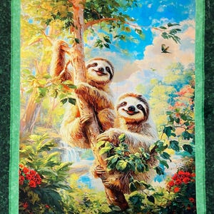 May include: A rectangular fabric wall hanging featuring a printed scene of two brown sloths climbing a tree in a lush forest. The artwork includes vibrant green foliage, red flowers, a blue sky with clouds, and a dark green fabric border.