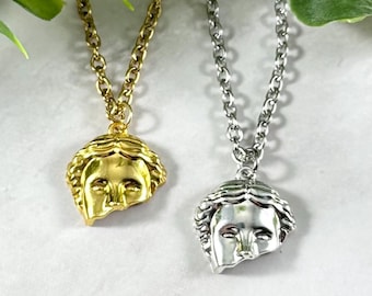 Peut inclure: Deux colliers avec des chaînes et des pendentifs en or et en argent. Les pendentifs sont tous deux des sculptures de visages brisés.