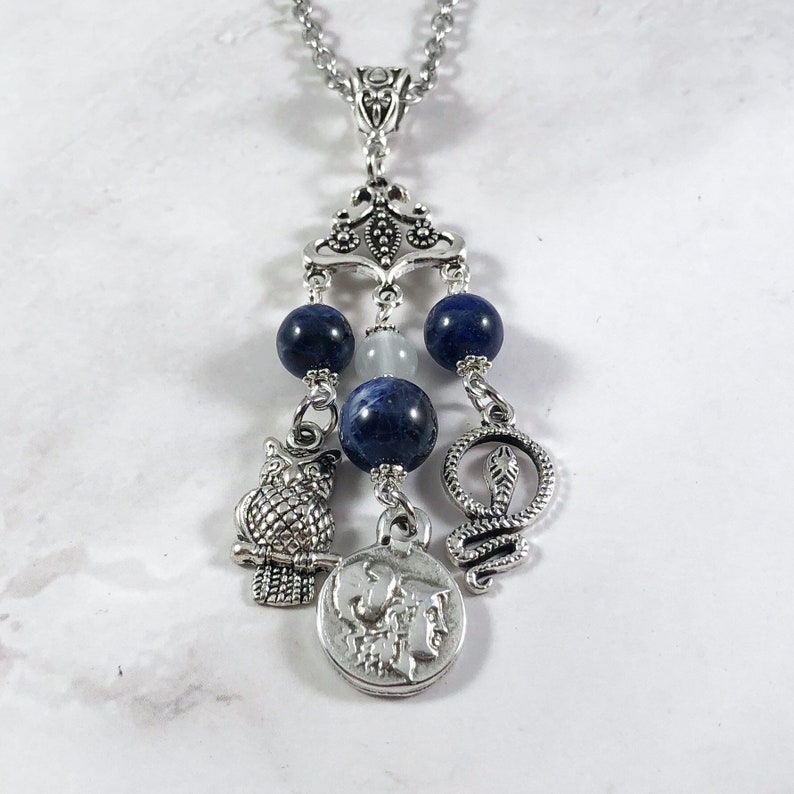 May include: Silver necklace with a blue and white stone charm, an owl charm, a snake charm, and a coin charm with a profile of a woman on it.