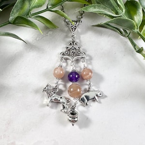 May include: A silver charm necklace with a sunstone and amethyst beads, a lion, a pig, and a cauldron charm.