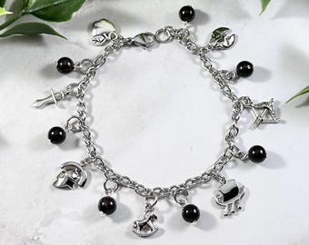 May include: A silver charm bracelet with black beads and various silver charms, including a sword, a horse, a helmet, a bow and arrow, and a ship.