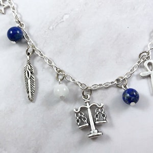 May include: A silver charm bracelet with various charms, including a feather, a scale of justice, a white bead, and blue lapis lazuli beads.