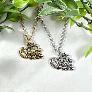 Puede incluir: Dos collares con un dije de plata y oro de un erizo enroscado con detalles florales.