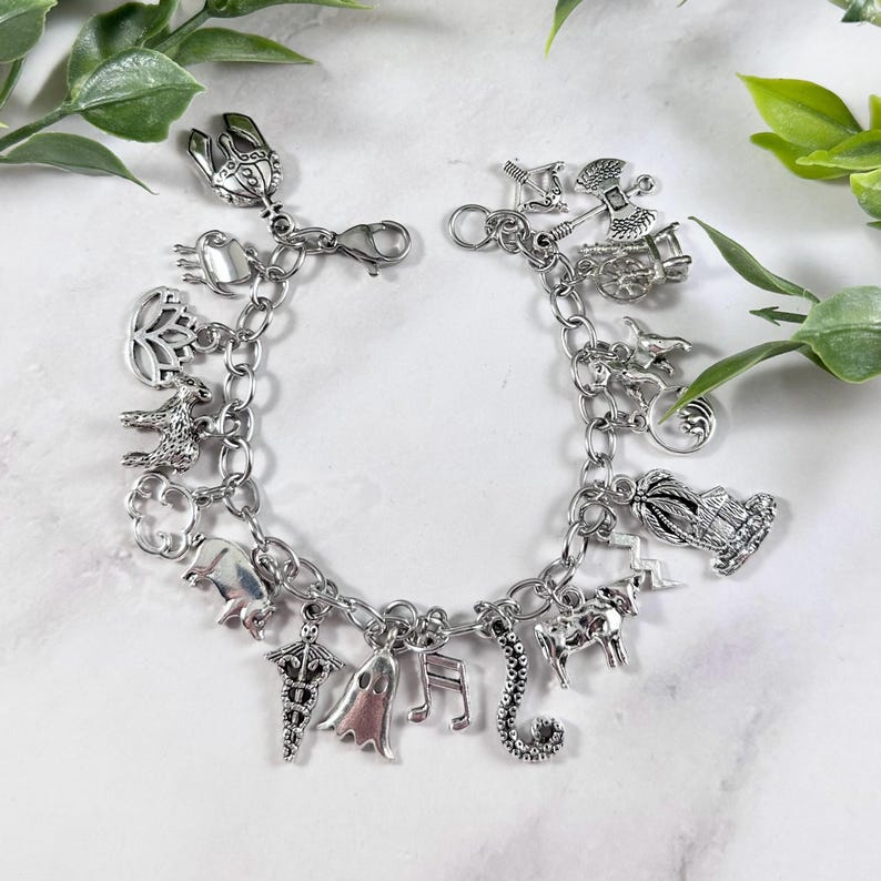 May include: A silver charm bracelet featuring a range of charms, including a ghost, a musical note, a seahorse, a unicorn, a lightning bolt, a palm tree, a crescent moon, a ram, a lotus flower, a crab, a scorpion, a crown, and a chariot.