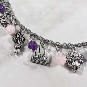 May include: A silver charm bracelet with pink and purple beads, and charms of a wheat sheaf, a flame, and a tree.