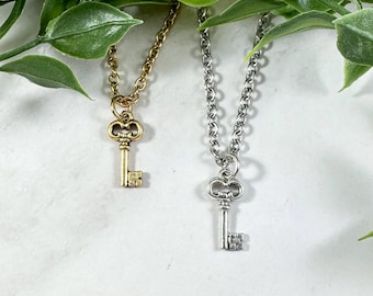 May include: Two delicate key necklaces, one with a gold key pendant and the other with a silver key pendant. Both necklaces feature a simple chain style.