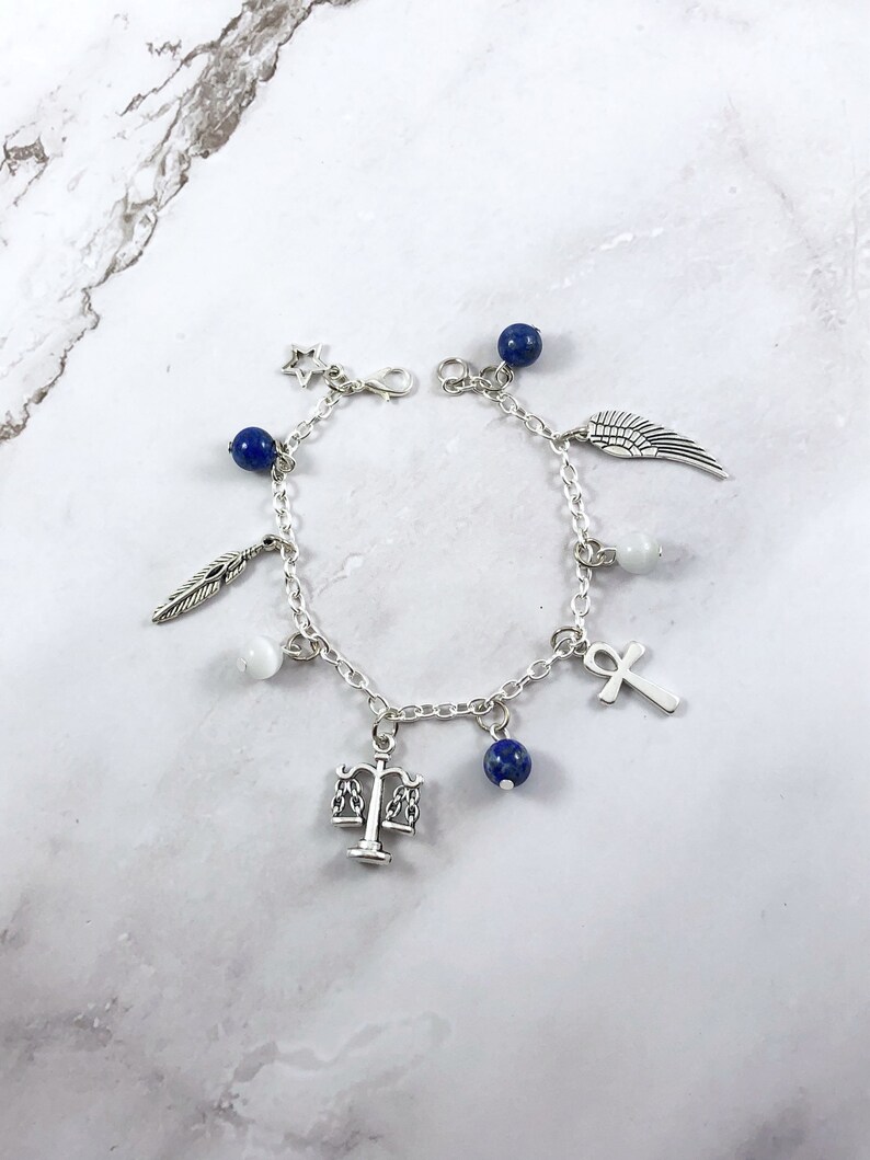 May include: A silver charm bracelet with blue and white beads, and charms including a feather, a star, a wing, a scale, an ankh, and a white stone.