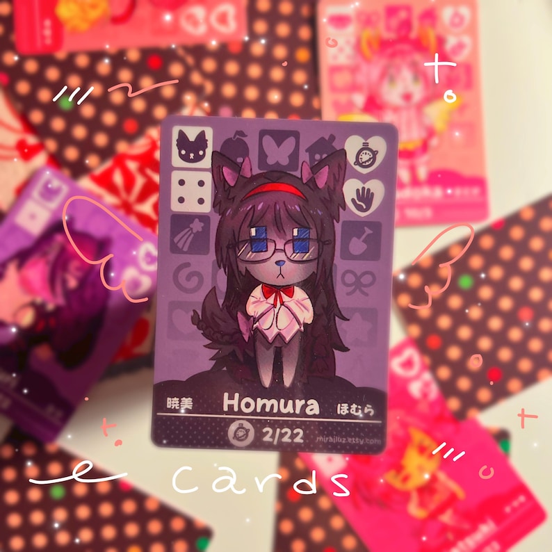 K&ouml;nnte beinhalten: Eine rechteckige Sammelkarte mit violettem Hintergrund und einer zentralen Illustration einer dunkelhaarigen Figur mit Katzenohren und Brille. Die Karte zeigt den Text Homura, 2/22 sowie verschiedene kleine Symbole wie einen Schmetterling.
