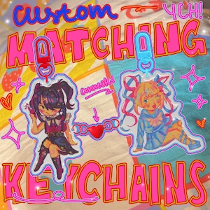 May include: Custom matching keychains with anime-style illustrations. The keychains feature two characters, one with dark hair and the other with blonde hair, connected by a heart-shaped charm. The text "MATCHING KEYCHAINS" is displayed in pink with a yellow outline.