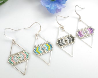 May include: Three pairs of silver geometric earrings with colourful beaded designs. The earrings are in the shape of a diamond with a beaded rectangle in the centre. The beads are in various colours, including pink, blue, green, black, and white.