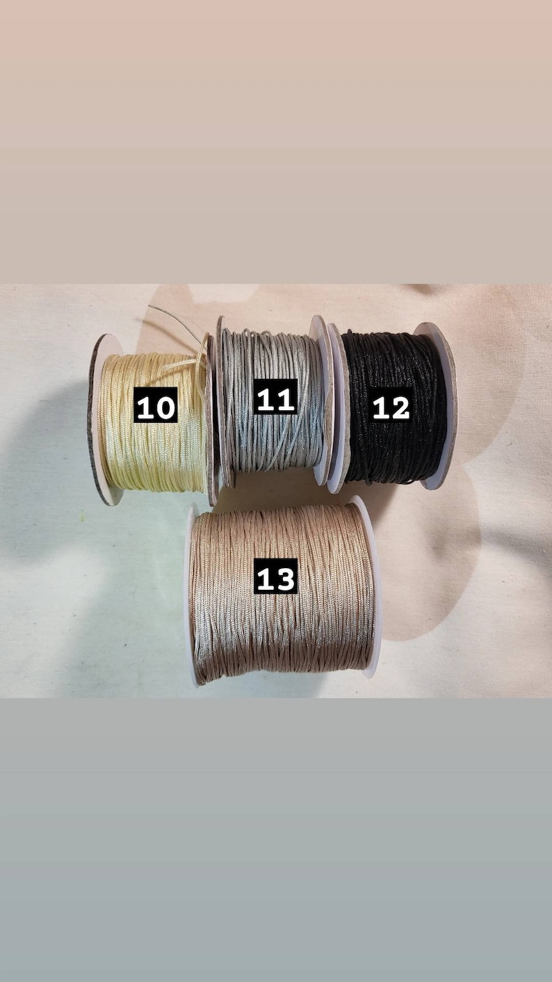 May include: Four spools of thread in different colours: beige, light grey, black, and a darker grey. The spools are labelled with numbers 10, 11, 12, and 13.