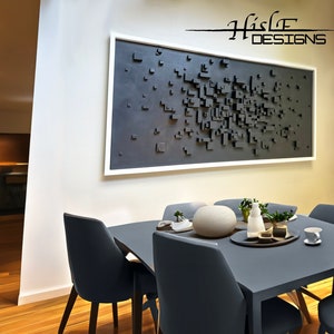 May include: A dark gray square wall art piece with a white frame hangs above a dark gray square table with four dark gray chairs. The table is set with a white cup and saucer, a small potted plant, and a decorative bowl.