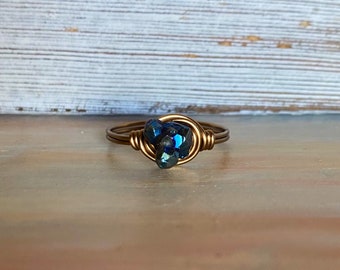 May include: A gold wire wrapped ring with a blue iridescent gemstone.