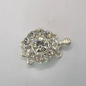 May include: Silver tone clasp with a large clear rhinestone in the center surrounded by smaller clear rhinestones.