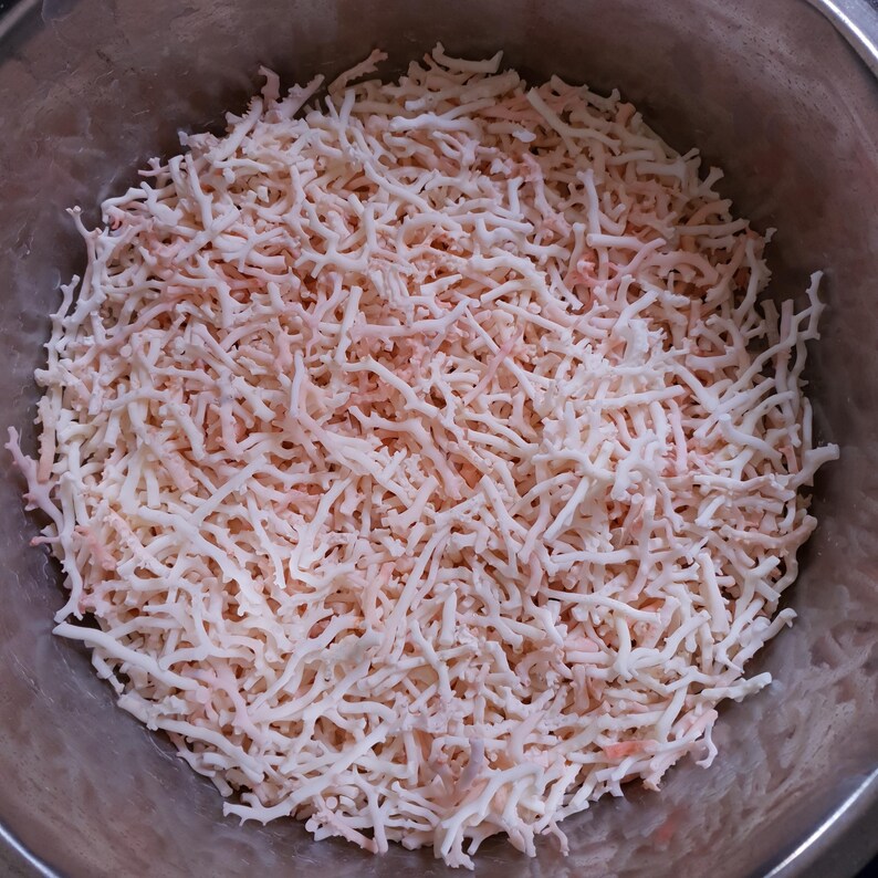 May include: A bowl filled with thin, white and pink strands of dried seaweed.