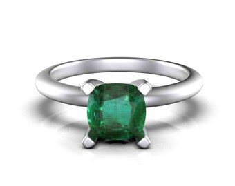 Op de afbeelding: Een zilveren ring met een vierkant geslepen, levendig groene smaragd. De ring heeft een gladde, gepolijste band en vier klauwen die de smaragd vasthouden. De edelsteen is het middelpunt, met zijn rijke kleur en helderheid.