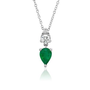 May include: A silver necklace with a pear-shaped emerald pendant and a round diamond accent. The emerald is a vibrant green color, and the diamond sparkles. The necklace hangs from a delicate chain, creating an elegant look.