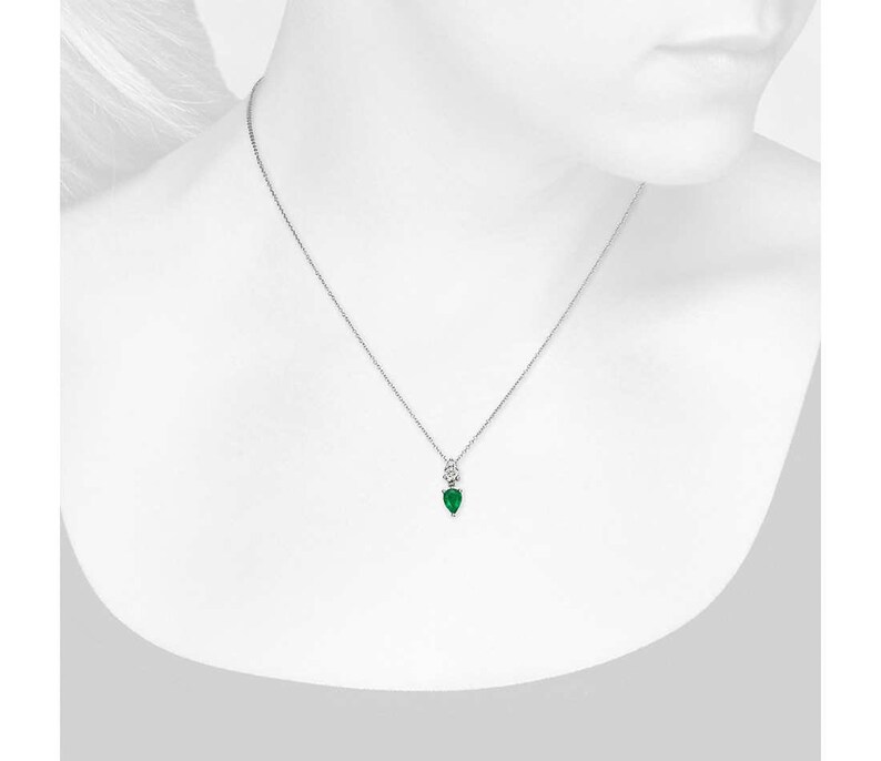 May include: A delicate silver necklace featuring a pear-shaped, emerald-green gemstone pendant. The pendant is accented with a small, round, clear stone above it. The necklace is displayed against a white background.