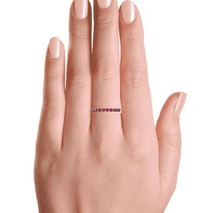 K&ouml;nnte beinhalten: Ein zarter Ewigkeitsring mit einer Reihe kleiner, runder roter Edelsteine, die in eine d&uuml;nne Metallband gefasst sind.