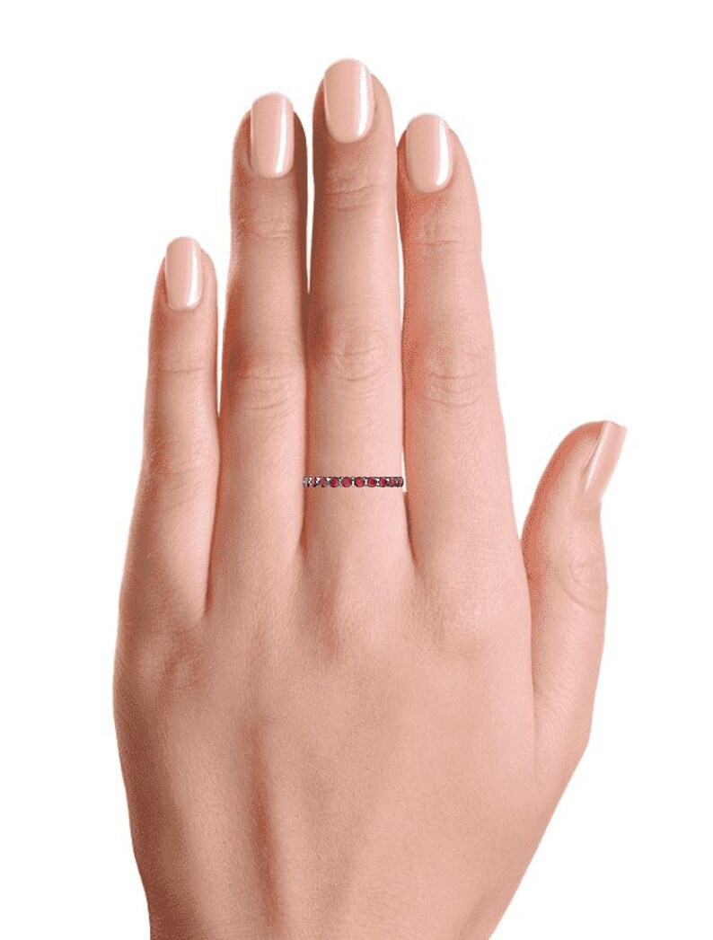 K&ouml;nnte beinhalten: Ein zarter Ewigkeitsring mit einer Reihe kleiner, runder roter Edelsteine, die in eine d&uuml;nne Metallband gefasst sind.