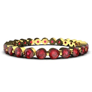 K&ouml;nnte beinhalten: Ein Goldring mit einer Reihe roter Edelsteine. Der Ring ist mit runden, gefassten Steinen besetzt.