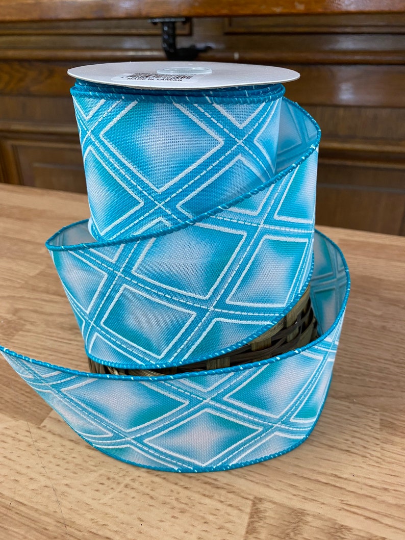 May include: A roll of blue and white patterned ribbon with a diamond design. The ribbon is 2.5 inches wide and has a wired edge.