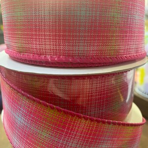 May include: Pink and green plaid ribbon with a wired edge. The ribbon is made of a textured fabric and has a subtle sheen.