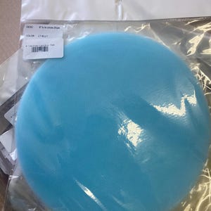 May include: A package containing a light blue tulle circle. The label reads "8" tulle circle-25/pk" and "LT BLUE". The tulle is a soft, mesh-like fabric, and the circle is visible through the clear plastic packaging.