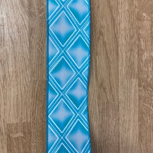 May include: A blue and white ribbon with a diamond pattern. The ribbon has a light blue background with white diamonds.