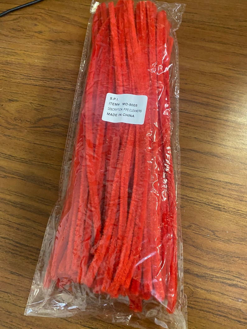 Puede incluir: Una bolsa de limpiapipas rojos. La bolsa tiene una etiqueta que dice "S.P.I. ITEM# MD-9005 DESCRIPTION: PIPE CLEANERS MADE IN CHINA."