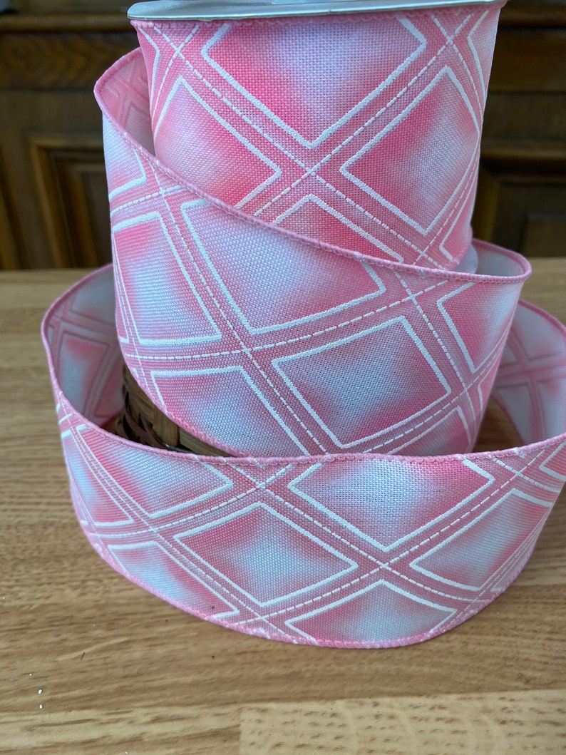 May include: Pink and white ribbon with a diamond pattern. The ribbon is made of a soft, textured fabric and has a subtle sheen.