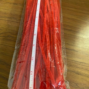 Puede incluir: Un paquete de limpiapipas rojos, que miden 30,5 cm de largo, se muestra sobre una superficie de madera.
