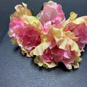 May include: A bouquet of three artificial peonies with pink and yellow petals. The flowers are arranged in a cluster and have a realistic appearance.