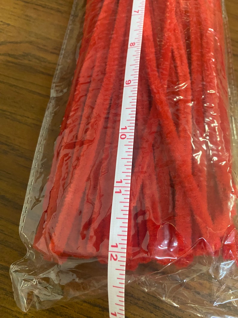Puede incluir: Primer plano de un paquete de limpiapipas rojos. El paquete es de pl&aacute;stico transparente y los limpiapipas est&aacute;n agrupados. Una cinta m&eacute;trica blanca es visible a lo largo del lado del paquete, mostrando medidas en pulgadas.