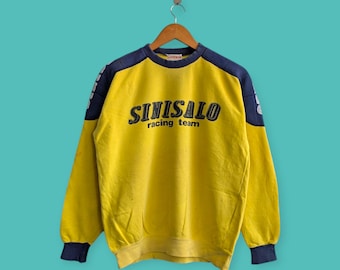 May include: Yellow sweatshirt with navy blue shoulder and sleeve accents. The front displays the text "SINISALO racing team". It has a crew neck and ribbed cuffs and hem. A vintage item.