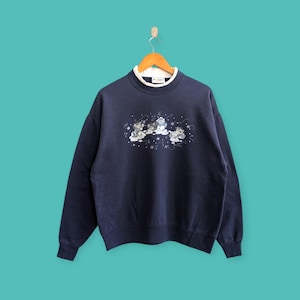 Puede incluir: Una sudadera azul marino con cuello interior blanco y un gráfico de cuatro gatitos de dibujos animados con gorros y bufandas de invierno sobre un fondo nevado.