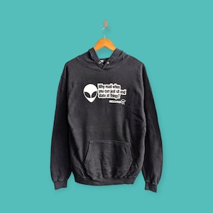 Puede incluir: Sudadera con capucha gris oscuro con bolsillo delantero y capucha. La sudadera presenta un gráfico de cabeza alienígena blanca y el texto: "¿Por qué leer cuando puedes simplemente sentarte y mirar las cosas?" La marca "BESCHWA" también está impresa.