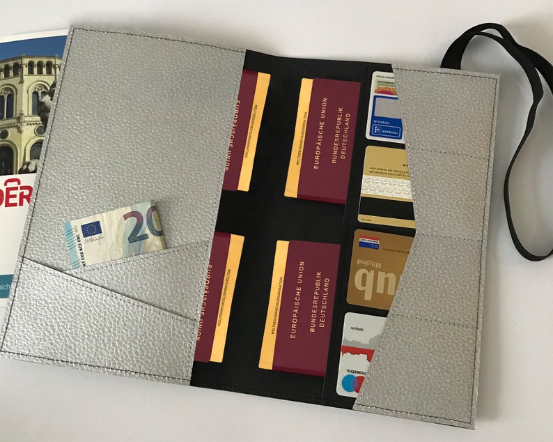 May include: A gray leather travel wallet with multiple pockets and a strap. The wallet is open and shows a passport, credit cards, and cash.