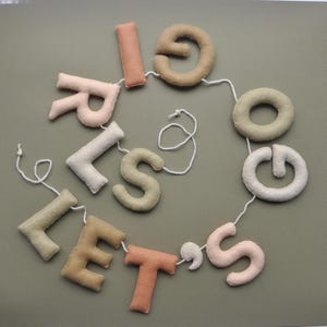 May include: A felt letter banner with the words "Let's Go Girls" in various shades of brown, beige, and pink.