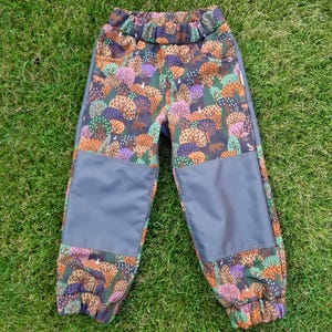 Op de afbeelding: Grijze en bruine geprinte broek met een bos scène. De broek heeft een donkergrijs paneel op elke knie.