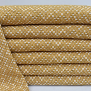 Op de afbeelding: Een stapel van acht gele keukendoeken met een wit geruit patroon en witte franjes.