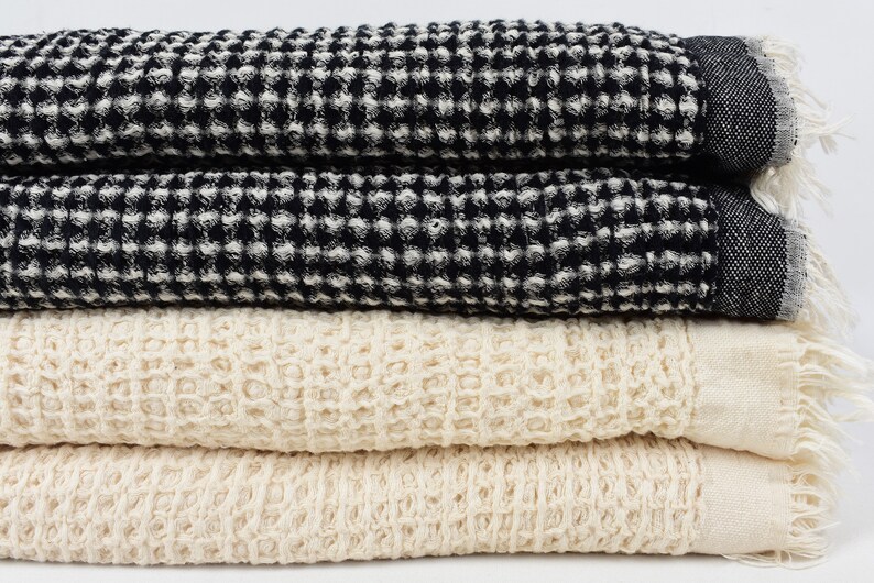 May include: A stack of four waffle weave towels in black and white and cream. The towels have a textured waffle weave pattern and are folded neatly.