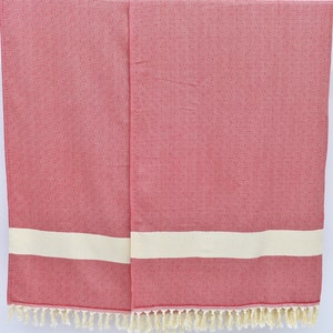 May include: Two red and white striped towels with fringe on the bottom. The towels are hanging on a wooden rod.